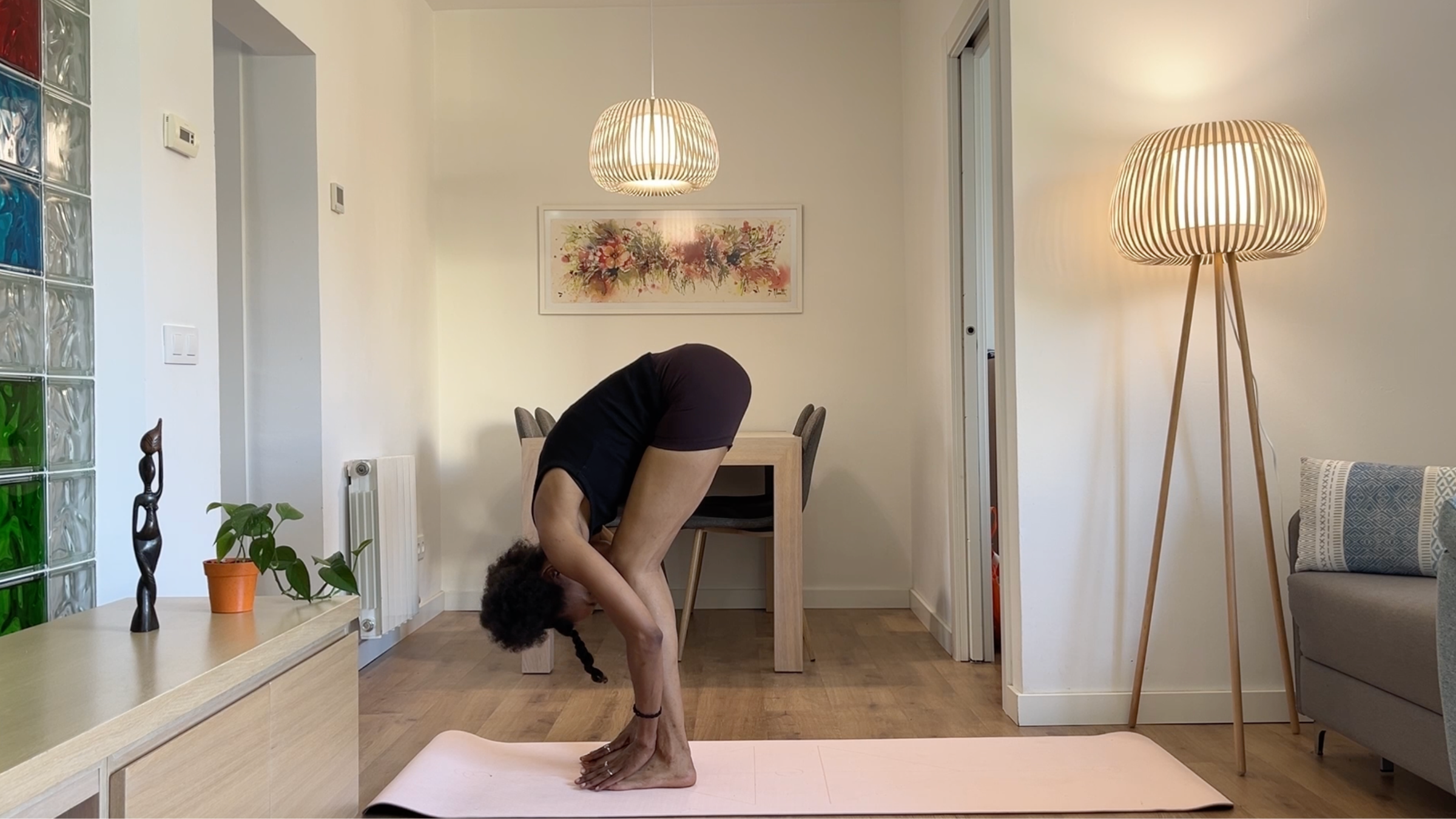 A person folding forward from the hips with their chest resting near their thighs, hands resting on the yoga mat, and head and neck completely relaxed.